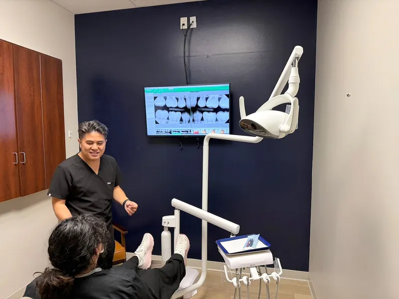 Dr. Chiem explains a panoramic X-ray on the wall screen to a patient in the chair