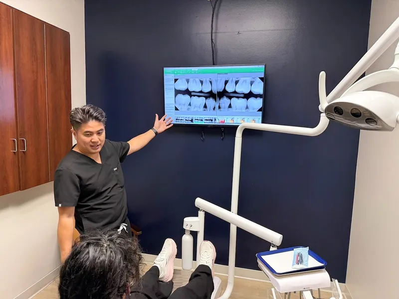 Dr. Chiem points to a panoramic X-ray while a patient looks on from the chair