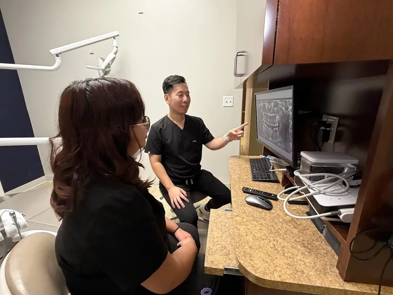 Dr. Tam points to an X-ray on the monitor while a patient listens
